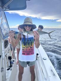 A joyful moment on the water as a woman proudly displays her catch while fishing with friends — a perfect day for fishing adventures.