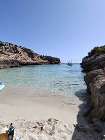 A picturesque beach scene with clear waters and boats anchored nearby, perfect for a relaxing day of swimming and enjoying the sun.
