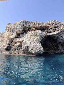 A stunning view of a rocky cave along the coastline, with kayakers exploring the area — a perfect destination for adventure seekers and nature lovers.