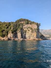 A stunning view of a rocky coastline with visitors exploring the shore, capturing the beauty of nature and adventure on the water.