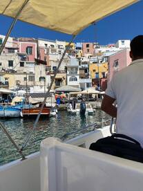 A scenic view from a boat approaching a vibrant harbor, showcasing colorful buildings and local boats — a perfect representation of coastal exploration.