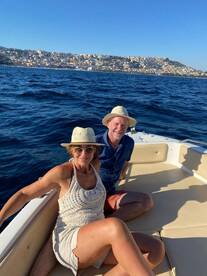 A couple enjoys a sunny day on a boat, capturing the essence of relaxation and adventure on the water with a beautiful coastal backdrop.