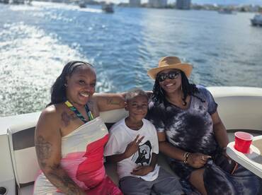 A joyful family enjoys their time on a boat, capturing a memorable moment with smiles and a beautiful water backdrop — perfect for family outings and celebrations.