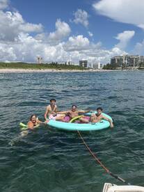 A lively group enjoys a sunny day on a floating mat in the water, perfect for family fun and relaxation at the beach.