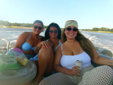Three friends enjoy a fun day on a pontoon boat, sipping drinks and soaking up the sun — perfect for a summer getaway on the water.