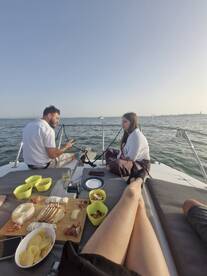 A couple enjoys a relaxing moment on a boat, sharing snacks and drinks while taking in the scenic views — perfect for a laid-back day on the water.