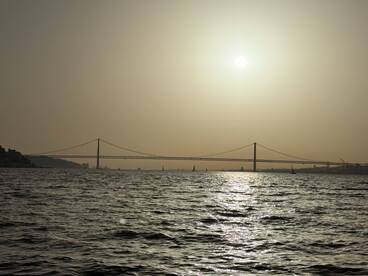A stunning sunset view featuring a bridge silhouetted against the horizon, creating a picturesque scene over the water.