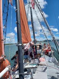A lively group enjoys a sailing experience on a sunny day, showcasing the camaraderie and excitement of being on the water.