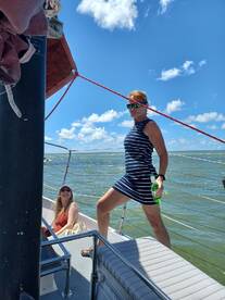 Two women enjoy a sunny day on a boat, one striking a pose with a drink while the other smiles, capturing the essence of a fun day on the water.