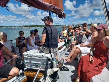 A lively group enjoys a sunny day aboard a boat, sharing drinks and laughter — perfect for a memorable boat party experience.