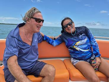 A joyful couple enjoys their time on a boat, smiling and relaxing under the sun — a perfect moment for ocean adventures.