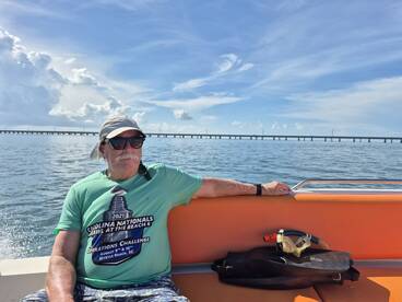A man relaxes on a boat with snorkeling gear nearby, enjoying the serene waters of Myrtle Beach, SC — perfect for aquatic adventures.