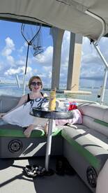 A young girl enjoys a relaxing moment inside a pontoon boat, showcasing the comfortable seating and scenic waterfront views.