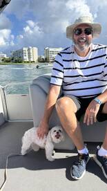 A man enjoys a sunny day on the boat with his playful dog, showcasing a perfect moment of relaxation and companionship on the water.