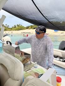 A chef grills delicious food on a boat, surrounded by a beautiful beach setting — perfect for onboard dining experiences.