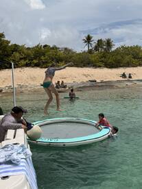 A fun-filled moment as kids enjoy jumping on a water trampoline while others relax nearby — perfect for family beach days and water activities.