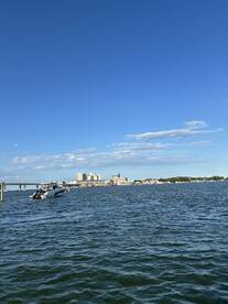 A scenic view of a boat navigating through the water with a vibrant city skyline in the background, perfect for showcasing waterfront adventures.
