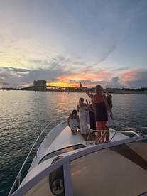 A lively group celebrates at sunset aboard a yacht, capturing the perfect moment against a stunning backdrop — ideal for unforgettable gatherings on the water.