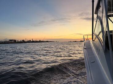 A serene sunset view featuring a boat's profile against a picturesque harbor, perfect for showcasing tranquil evening cruises.