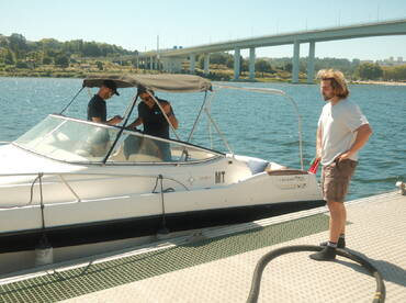 Three individuals interact on a boat at the dock, showcasing a lively atmosphere perfect for boating adventures.