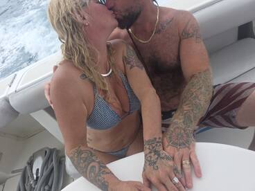 A couple shares a romantic kiss aboard a boat, capturing a special moment on the water — perfect for celebrating love and connection.