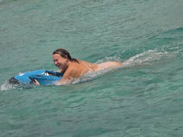 A woman enjoys a thrilling ride on a jet ski in crystal-clear waters, showcasing the excitement of water activities during a perfect day on the boat.