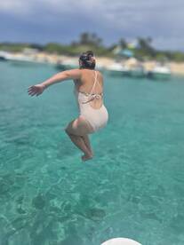 A woman joyfully leaps into the crystal-clear waters, capturing the essence of summer fun and adventure on the water.