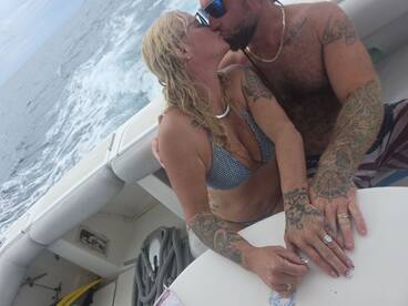 A couple shares a romantic kiss aboard a boat, surrounded by the ocean — a perfect moment for love on the water.