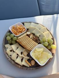 A beautifully arranged charcuterie board featuring cheese, crackers, grapes, and snacks, perfect for enjoying on a boat trip.