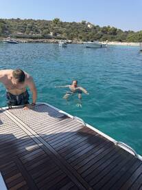 Two friends enjoy a refreshing swim in crystal-clear waters, showcasing the perfect summer day on the boat.