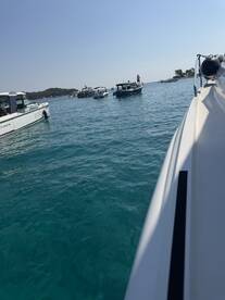 A scenic view of multiple boats navigating through clear turquoise waters, showcasing the beauty of a vibrant boating destination.