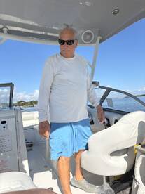 A man stands at the helm of a boat, showcasing the interior layout with a focus on the console and seating area, perfect for navigating the waters.