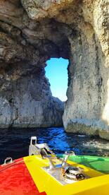 A stunning view of a natural rock formation with a hole, seen from a colorful boat — a picturesque moment capturing the beauty of coastal exploration.