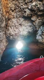 A stunning view from inside a rocky cave, with sunlight streaming through the opening, creating a picturesque scene perfect for exploration adventures on the water.