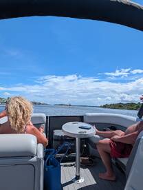 A couple enjoys a relaxing day on a pontoon boat, soaking in the sun and scenic views along the waterway.