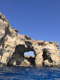 A stunning view of natural rock formations against a clear blue sky, showcasing the beauty of coastal landmarks — perfect for sightseeing and exploration during boat trips.