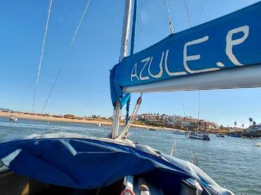A view of the sailboat 'AZULE.P' as it navigates through calm waters, showcasing the beautiful coastal scenery in the background.