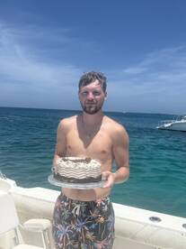 A man celebrates with a cake on a boat, perfect for birthday parties or special occasions on the water.