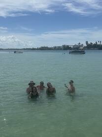 A fun group enjoys a refreshing swim in shallow waters during a sandbar stop, creating unforgettable memories on their boating adventure.