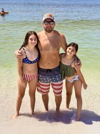 A joyful family poses together in shallow water at the beach, capturing a perfect moment of summer fun and togetherness.