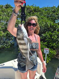 A woman proudly displays her catch of the day while fishing, showcasing the thrill of angling in a scenic waterway.