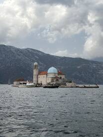 A picturesque view of an island landmark with a church, surrounded by mountains and water, showcasing the beauty of coastal destinations.