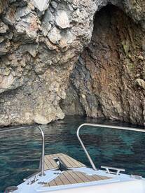 A stunning view of a rocky cave entrance from the bow of a boat, showcasing the beautiful coastal scenery and crystal-clear waters.