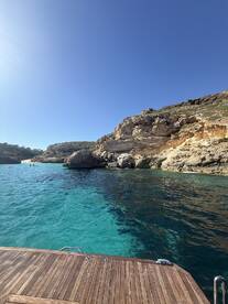 A stunning view of turquoise waters and rocky coastline, with people enjoying the serene surroundings — perfect for a day of exploration and relaxation on the water.