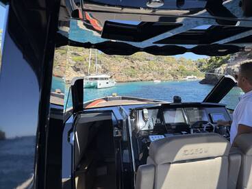 A view of the helm inside a sleek boat, showcasing the modern console and navigation equipment, perfect for a day of exploring beautiful coastal waters.