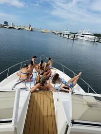 A lively group enjoys a day on the water, sunbathing and relaxing on the deck of a boat, perfect for summer outings and celebrations.