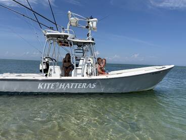 A group of friends enjoys a sunny day on the water aboard the Kite Hatteras, perfect for fishing and fun in the sun.