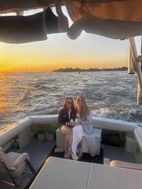 Two friends enjoy drinks on a boat at sunset, creating a perfect backdrop for memorable moments on the water.
