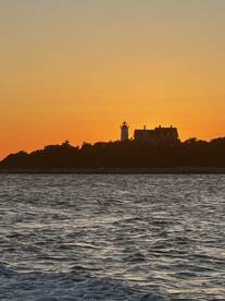 A stunning sunset view featuring a lighthouse silhouetted against the vibrant orange sky, perfect for capturing the beauty of coastal scenery.