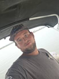 A selfie of a man on a boat, with a view of the water in the background. The image lacks clarity regarding the boat's features or activities.
